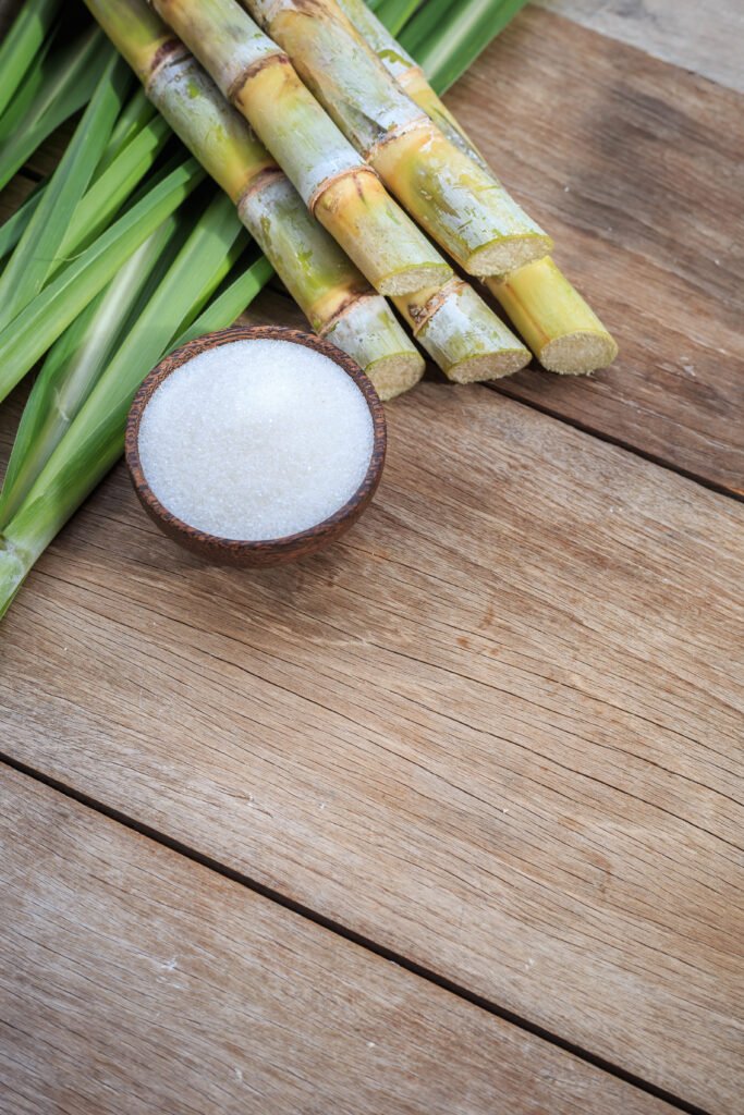 Top view white sugar and sugar cane and leaf on wooden